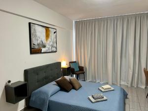 LivadhiaFatCow Seaside Suites的一间卧室配有一张蓝色的床、椅子和窗户
