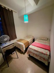 贝洛奥里藏特Cool Living Hostel - Praça da Liberdade的客房设有两张床、一张桌子和风扇。