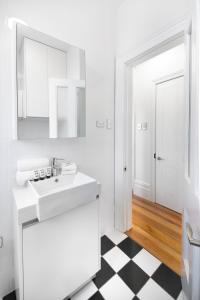 悉尼Not your usual studio apartment的浴室铺有黑白格格子地板,配有白色水槽。