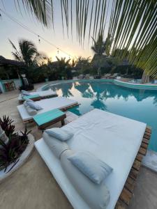 江比阿Zen Boutique Resort的一座游泳池,拥有几张白色的床和棕榈树