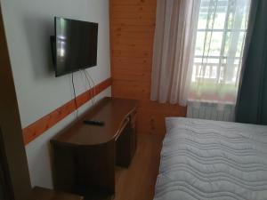 贝拉内Etno Selo VRELO & CAMPING Bikers friendly的一间卧室配有一张床,墙上配有电视