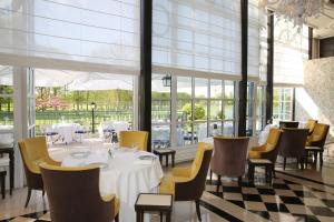 凡尔赛Waldorf Astoria Versailles - Trianon Palace的一间带桌椅和窗户的用餐室