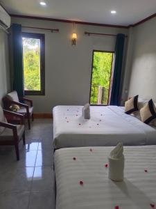 万荣Dokchampa Hotel的两张床位于带红色鲜花的房间
