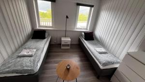 GratangenStorfossen Hostel的客房设有两张床、一张桌子和两个窗户。