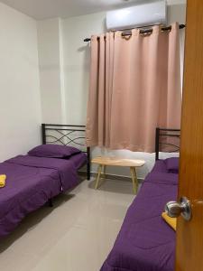 莎阿南Igo Homestay Subang Airport的配有紫色床单和窗帘的客房内的两张床