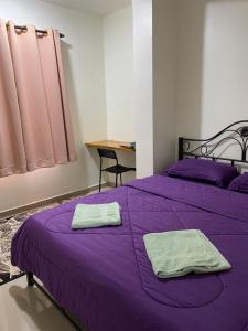 莎阿南Igo Homestay Subang Airport的紫色的床,上面有两条毛巾