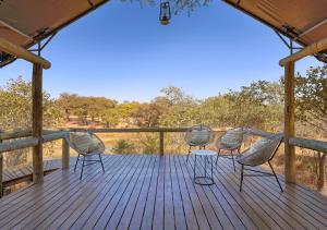 MababeHideaways Mogotlho Safari Lodge, Khwai River的四把椅子坐在木制甲板上,享有旷野的景色