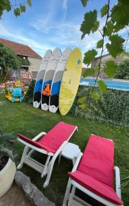 比耶拉Family House with pool & sea view的草地上设有两把椅子和一把椅子及冲浪板