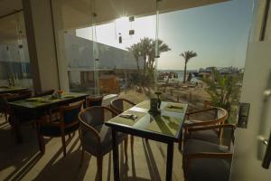 赫尔格达Shellghada Blue Beach的一间带桌椅的餐厅,享有海滩美景