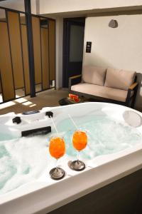乐托卡亚CORYLUS Luxury Rooms & Suites的浴缸里放着两杯橙色鸡尾酒