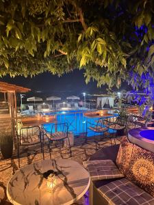 雷夫卡达镇塞米勒米斯酒店的一个带桌椅的庭院和一个夜间游泳池