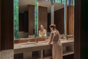 拉威海滩Stay Wellbeing & Lifestyle Resort的站在浴室镜子前的妇女