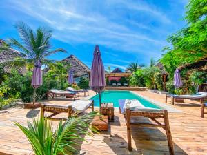帕杰Ananda Beach Hotel的度假村的游泳池,配有椅子和遮阳伞