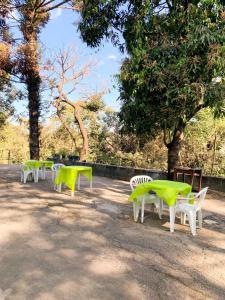MatozinhosHotel Aconchego Matozinhos的一排绿桌和椅子在树下