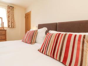 洛斯特威希尔Byre的卧室配有一张带两个条纹枕头的白色床