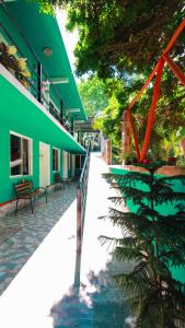 巴卡拉尔Hotel Vias Maya Bacalar的一座绿色建筑,前面有棕榈树