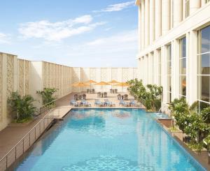 孟买泰姬陵圣克鲁斯酒店的一个带桌椅的酒店游泳池的 ⁇ 染