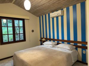 布希奥斯Pousada Peninsula de Buzios的一间卧室配有一张带条纹墙的床