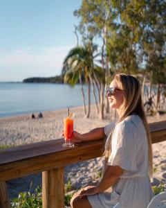 大克佩尔岛大克佩尔岛海德威度假酒店的坐在围栏上的女人在沙滩上喝一杯