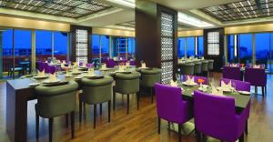 安曼安曼公司酒店的餐厅设有紫色椅子、桌子和窗户