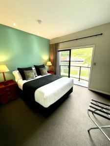 吉斯伯恩Portside Hotel Gisborne的一间带大床的卧室和一个阳台