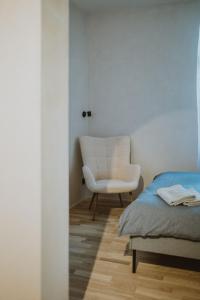 采西斯Garden House Apartments的一间卧室配有一张床和一张白色椅子
