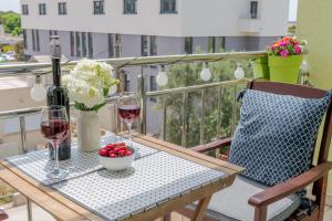 特罗吉尔Trogir Downtown Apartments的阳台上的桌子上摆放着酒杯和鲜花