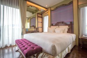 清迈禅凯姆精品酒店的一间大卧室,配有一张大床和一张紫色长椅