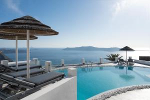 易莫洛林Santorini Princess Spa Hotel的一个带椅子和遮阳伞的游泳池以及大海