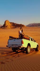 瓦迪拉姆wadi rum camp stars & jeep tour的坐在沙漠中一辆卡车后面的女人