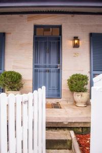 悉尼Balmain Sandstone Cottage的一座带蓝色门和白色围栏的房子