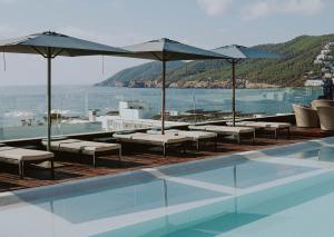 圣埃乌拉利亚Aguas de Ibiza Grand Luxe Hotel - Small Luxury Hotel of the World的一个带椅子和遮阳伞的游泳池以及大海