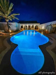 米多恩Maison Leila chambres d hotes的夜间带蓝色灯光的大型游泳池