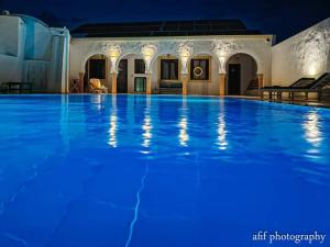 米多恩Maison Leila chambres d hotes的夜间大型游泳池,拥有蓝色照明