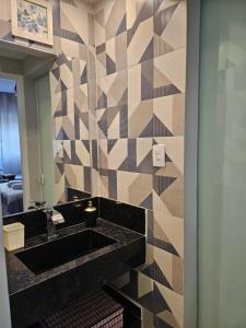 桑托斯Apartamentos na Praia do Gonzaga的浴室设有黑色水槽和镜子