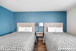 温斯顿·塞勒姆WoodSpring Suites Winston-Salem near Hanes Mall的蓝色墙壁客房的两张床