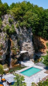 雷梅齐乡Pensiunea Apuseni Wild的一座带瀑布的岩石山中的游泳池