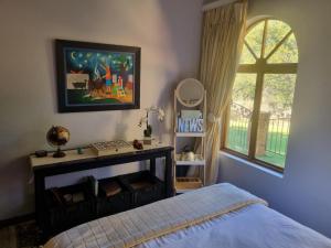 克鲁格斯多普Mind-Body-Soul Guesthouse on Featherbrooke Estate, Krugersdorp, South Africa的一间卧室设有一张床和一个窗口