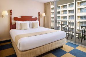 檀香山威基基伊娃酒店的一间带大床的卧室和一个阳台