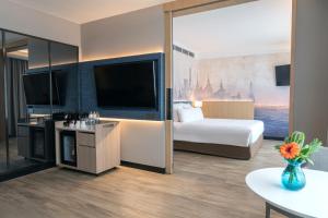 曼谷诺福特暹罗广场酒店的配有一张床和一台平面电视的酒店客房