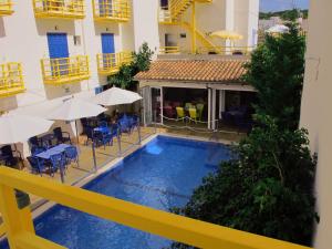 卡拉纳雅达Hotel Bellavista的一座带椅子和遮阳伞的建筑庭院内的游泳池