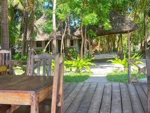 基林多尼Juani beach bungalows的坐在房子前面甲板上的木凳