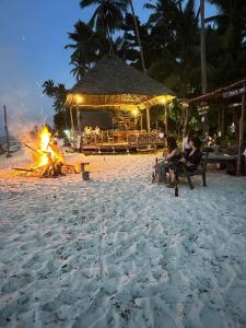 基林多尼Juani beach bungalows的一群人坐在海滩上的火堆旁