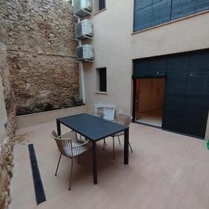 佩拉托拉达Empordà Apartamento- Peratallada的庭院里设有一张黑色的桌子和椅子,庭院里设有一座建筑