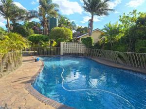 哈拉雷Beautiful 2-Bedroomed Guest Cottage in Harare的一个带围栏和棕榈树的游泳池