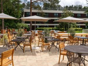圣艾蒂安迪鲁夫赖南鲁昂诺富特酒店的一个带桌椅和遮阳伞的户外庭院。