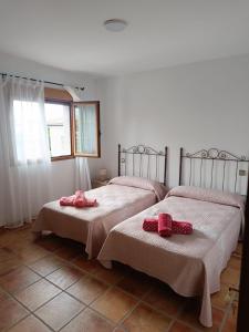 Casas del MonteAires Del Ambroz的一间卧室配有两张带粉红色弓的床铺。