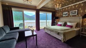 松达尔霍夫隆德峡湾酒店的一间卧室配有一张床、一张沙发和一个大窗户
