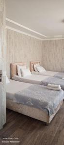 布哈拉Hotel Guest House GOLDEN DEGREZ的两张睡床彼此相邻,位于一个房间里