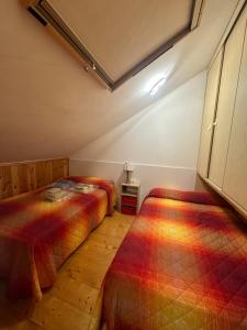 Albergo Monte RovereMini Appartamento Malga Laghetto的配有彩虹毯子的客房内的两张床